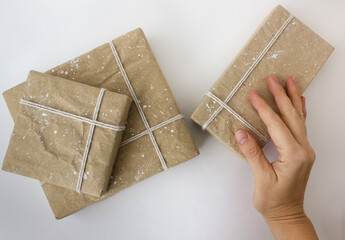 hand holds gift box wrapped in beige craft paper and tied with cotton thread. The concept of New...