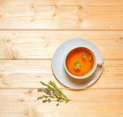 Herbal flower tea in a saucer cup on a warm wooden background.