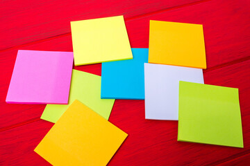 Multi Colored note paper on wooden background. Multi color square shape.