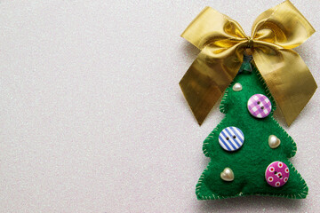 Homemade Christmas tree made of felt with bow on white glitter background