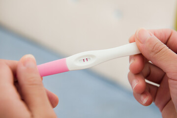 pregnancy test kit in female hand on blurred background.