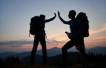 Family pair of hikers fun clapping each other's hands when they reached top of the mountain during...