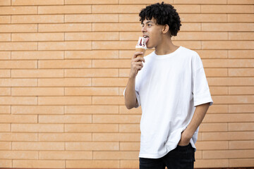 Lifestyle, dessert, sweets and people concept - Happy curly-haired African-American guy licking...