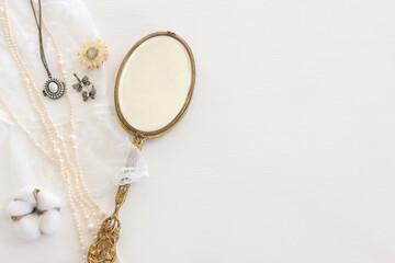 Background of white delicate lace fabric, pearls and vintage hand mirror