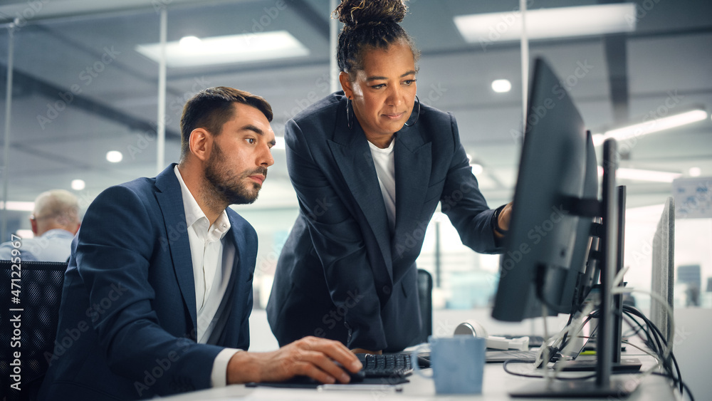 Poster senior manager talking to young confident businessman while using computer in modern office. colleag