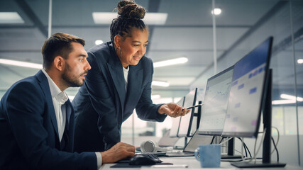 Senior Manager Talking to Young Confident Businessman while Using Computer in Modern Office. Colleagues Discuss Commercial, Financial and Marketing Projects. Specialists Work in Diverse Team.