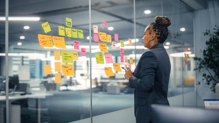 African American Businesswoman Creating Project Plan on Office Wall with Paper Notes. Stylish Confident Manager Working on Business, Financial and Marketing Projects. Specialist in Diverse Team.