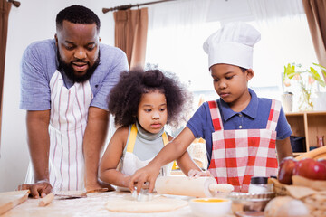 African American family help prepare the flour for making cookies. Happy African American family