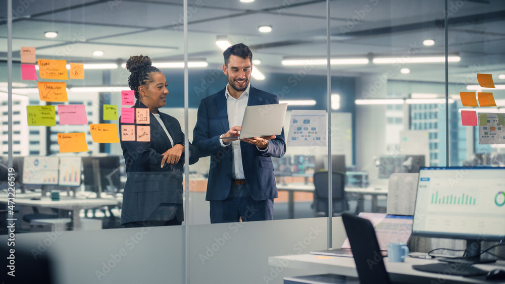 Poster Young Businessman Talking with Experienced Colleague while Using Laptop Computer in Office. Employees Discuss Corporate, Financial and Marketing Projects. Specialists Work in Diverse Team.