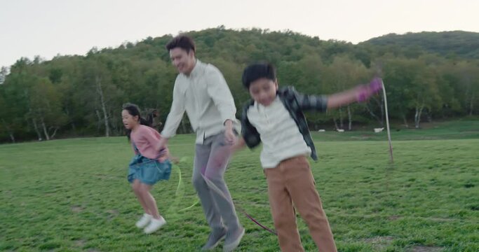 Happy young family jumping ropes outdoors,4K