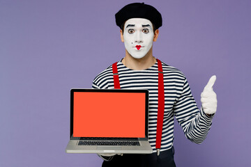 Young mime man white face mask in striped shirt beret hold use laptop pc computer with blank screen...