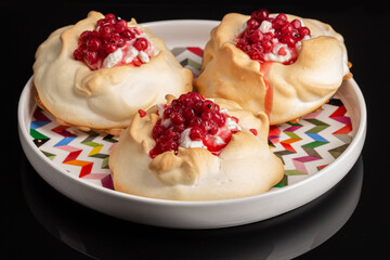 Red currant mini Pavlova cakes on black background