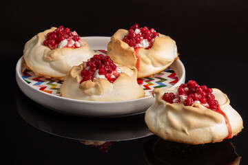 Red currant mini Pavlova cakes on black background