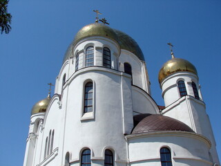 Panorama of gilded towers of the Orthodox Church illuminated by the sun against a clear blue sky.
