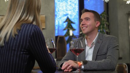 A man on a date with a woman in a cafe or restaurant drinking wine close-up