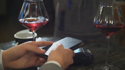 A man on a date with a woman pays a bill in a cafe or restaurant using NFC close-up