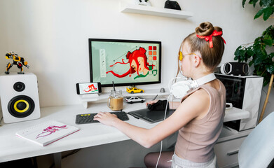 A young girl draws on a PC using a graphics tablet in her comfortable home office.
