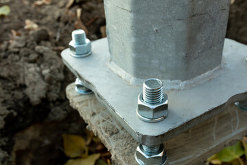 Metal pillar fastened to basement with anchor bolts and nuts. The support of the iron pillar.