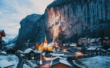 amazing touristic alpine village at night in winter with famous church and Staubbach waterfall ...