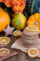 Top view of shortbread cookies with orange slices with cinnamon on wooden table with pumpkins, vertical