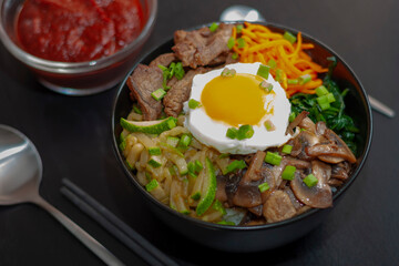 Pibimbap is a popular national dish of traditional Korean cuisine, made from rice, meat, zucchini, mushrooms, carrots, spinach, eggs. close-up.