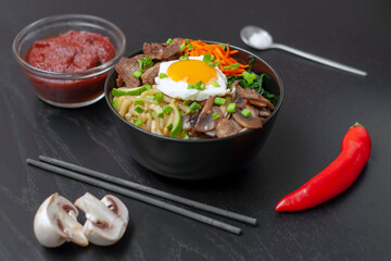 Pibimbap is a popular national dish of traditional Korean cuisine, made from rice, meat, zucchini, mushrooms, carrots, spinach, eggs. side view.