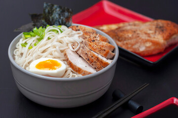 Ramen is a national, popular dish of traditional Japanese cuisine. Asian soup with wheat noodles, chicken breast, egg and broth. Side view.