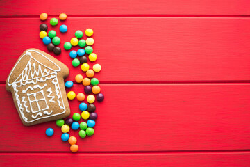 Gingerbread and colored sweets on a red  wooden background.  Place for text or logo.