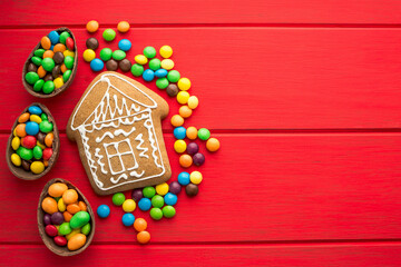 Gingerbread and colored sweets on a red  wooden background.  Place for text or logo.