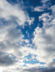 Big white fluffy clouds in the blue sky in sunny weather, vertical format