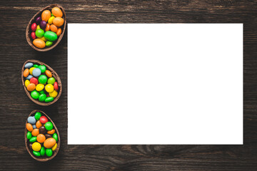 Chocolate easter eggs and colored sweets on a wooden background.  Place for text or logo.