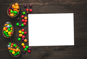 Chocolate easter eggs and colored sweets on a wooden background.  Place for text or logo.