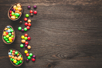 Chocolate easter eggs and colored sweets on a wooden background.