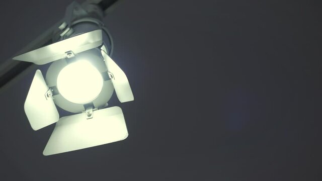 Ceiling spotlight on rail system in photo studio. HDR. Black soffit with cold light on grey ceiling background.