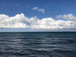 Naklejka na ściany i meble Amazing white clouds of type cumulus over dark blue colored ocean.