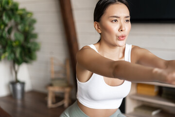 Obraz na płótnie Canvas Young asian fitness woman with healthy fit body, doing squats, morning workout, wearing activewear, standing at home in living room and having training session