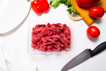 Raw beef stroganoff in plastic container on kitchen table