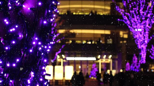 TOKYO, JAPAN - NOVEMBER 2021 : Christmas illumination, led light up and snow at Hibiya area. Scenery of downtown city and street at night. Soft snow falling. Winter and Christmas season concept.