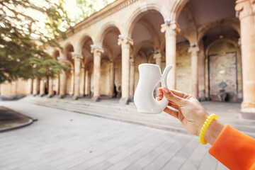 White cup for drinking hot mineral therapeutic water on the background of a gallery with columns. A...