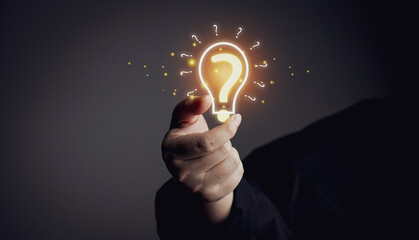 Doubts, new ideas and innovations arise and the search for answers. male hand holding a virtual light bulb with question mark icon