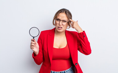 hispanic pretty woman feeling confused and puzzled, showing you are insane. magnifying glass concept