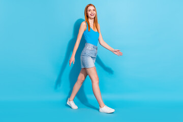 Photo portrait red haired woman in pretty singlet jeans skirt walking forward isolated pastel blue color background