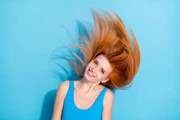 Portrait of attractive cheerful girl having fun throwing shine hair isolated over bright blue color background