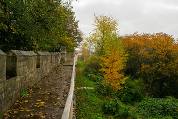 Trail on top of medieval 13th century city wall through colorful autumn foliage in York England