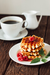 yummy belgian waffles with raspberries and mint leaves on wooden table 