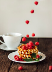 yummy belgian waffles with raspberries and mint leaves on wooden table 