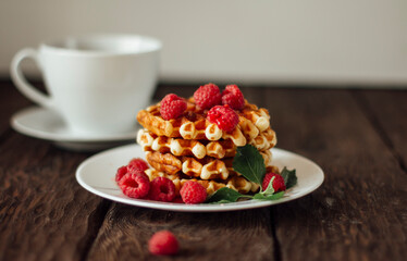 yummy belgian waffles with raspberries and mint leaves on wooden table 