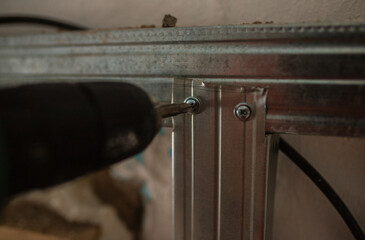Drives screws into the holder. Close-up, hand with a screwdriver tightening the fastening screw....