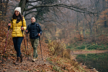 Smiling caucasian hikers, following the path through the forest.