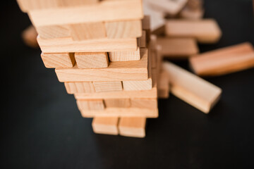 Education, risk, development and growth concept. jenga game. The businessman controls his strategy. Wooden blocks stack up game with copy space, background. wooden cubes on a black background jing gam